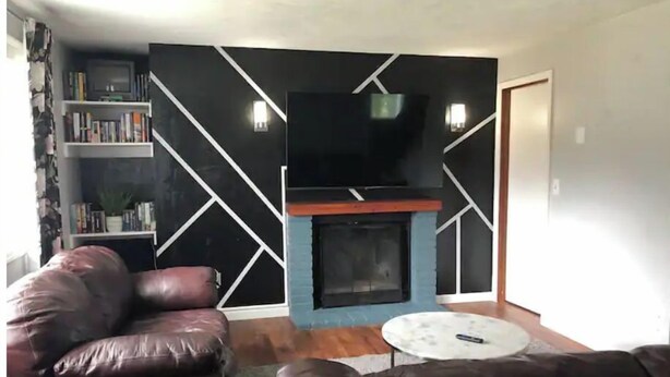 A living room with a fireplace, leather sofas, a bookshelf, and a flat-screen TV. - Cozy 3 Bedroom Unit (Olympia)