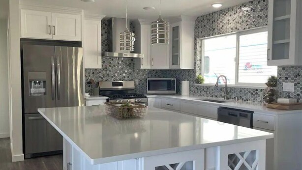 A modern kitchen with a central island, stainless steel appliances, and a stone backsplash. - New! Charming 4-Bedroom House (Des Moines)