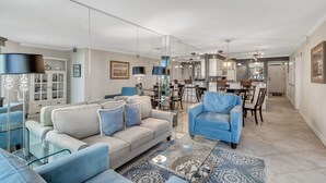 Amplia sala de estar con sofá, sillones y un comedor con sillas y mesa.