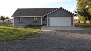 Une maison de plain-pied avec un garage, une pelouse devant et une allée.