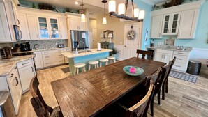 A modern kitchen with a wooden island, bar stools, and a dining table.