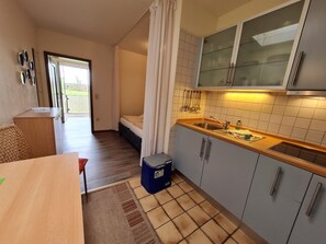 Una cocina compacta con pileta, alacenas y un comedor con mesa y sillas.