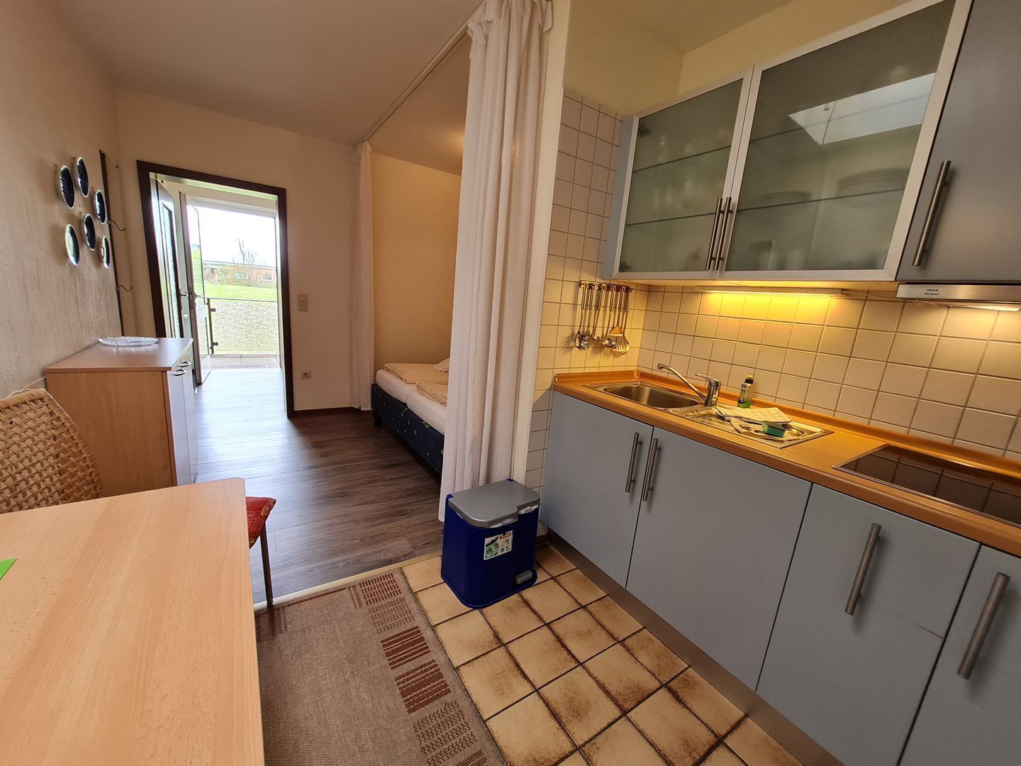 A compact kitchen with a sink, cabinets, and a dining area with a table and chairs.