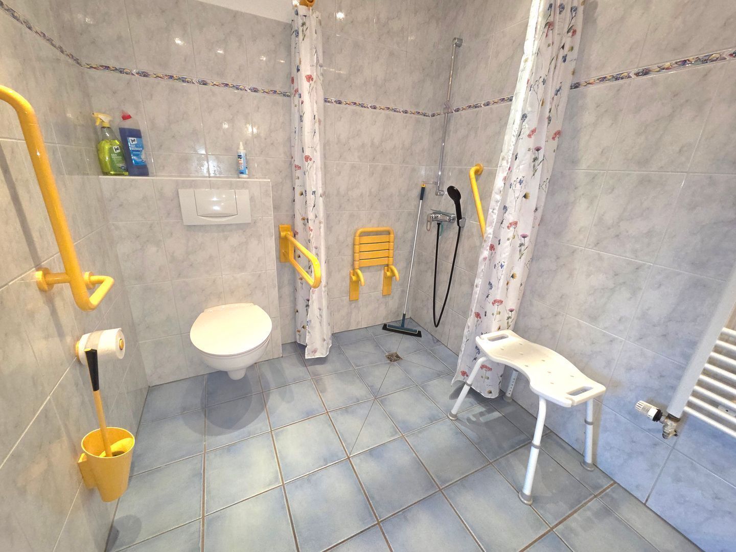 A bathroom with a toilet, shower, and a small white bench.