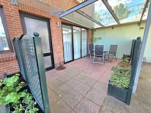 A patio area with a brick wall, a sliding glass door, a metal gate, and outdoor seating. - House Ekke Nekkepenn II, Whg. D1, close to the beach and the harbor - House Ekke (Wyk auf Föhr)
