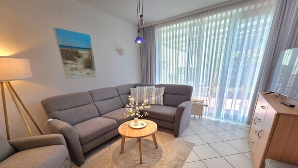 En moderne stue med en grå sofa, et sofabord og en lampe.