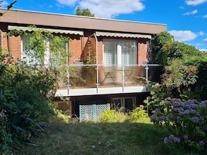 Ein zweistöckiges Haus mit Balkon, Backsteinmauern und einem Garten mit Hortensien.