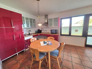 Eine kleine Küche mit Esstisch, Stühlen und einem roten Schrank.