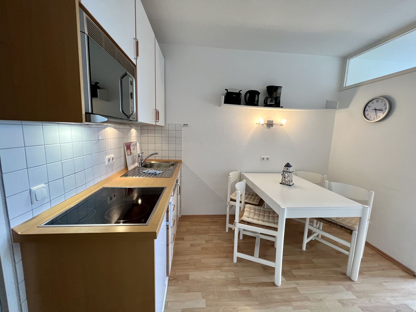 A compact kitchen with a built-in stove, a microwave, and a sink. There is a small dining area with a table and chairs.
