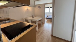A compact kitchen with a stove, a dining table, and a small window.