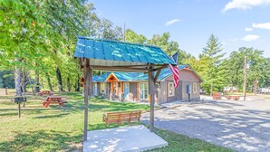 A rustic cabin with a blue roof, picnic tables, and a bench in a wooded area. - Relaxing, family friendly lodge by the lake. (Ten Mile)