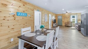 A wooden interior with a dining table, chairs, and a sign that reads "What happens at the lake stays at the lake." - Relaxing, family friendly lodge by the lake. (Ten Mile)