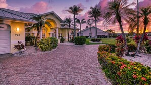 A residential property with a paved driveway, palm trees, and a well-maintained garden. - Intervillas Florida - Villa Manatee (Cape Coral)