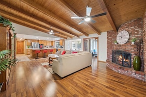 A spacious living area with a wooden ceiling, a fireplace, and a large clock on the wall.