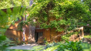 Une cabane rustique avec une façade en bois, un porche à l’avant et un escalier menant à l’entrée.