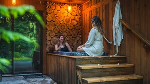 Une cabane en bois avec un jacuzzi, des marches en bois et un mur en pierre.
