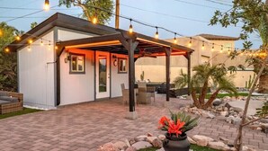 Un área de patio techada con una pérgola, asientos al aire libre y una planta en maceta.