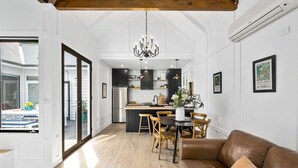 A modern kitchen with dark cabinets, a stainless steel refrigerator, and a dining area with a wooden table and chairs.