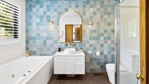 A bathroom with a bathtub, a sink with a mirror, and a toilet.