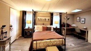 A four-poster bed with a canopy, bedside tables with lamps, a desk, and a chair in a room with wooden flooring and a ceiling light. - Inn the Woods - cozy place in the Smokies (Sevierville)