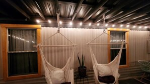 Two white hanging chairs with cushions, a potted plant, and a metal ceiling with exposed beams. - Inn the Woods - cozy place in the Smokies (Sevierville)