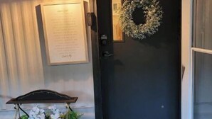 A black door with a wreath, a small cart with flowers, and a welcome mat. - Inn the Woods - cozy place in the Smokies (Sevierville)