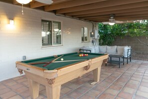 Enjoy a game of pool in the outdoor patio area, featuring a table and seating for relaxation.