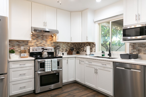 Enjoy cooking in this well-lit kitchen with an oven, dishwasher, and large window offering a view of the outdoors.