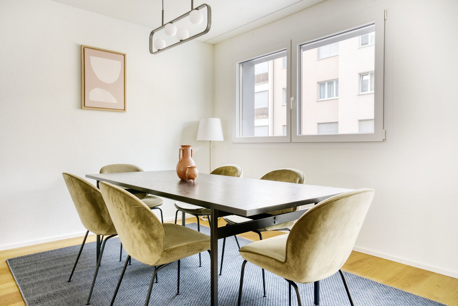Ein moderner Essraum mit einem rechteckigen Tisch, sechs Stühlen, einer Vase und einer Lampe.