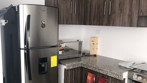 A modern kitchen with dark wood cabinets, a stainless steel refrigerator, a microwave, a built-in oven, and granite countertops. - SPA BEACH HOUSE con PLAYA PRIVADA/PISCINA/JACUZZI (Manta)