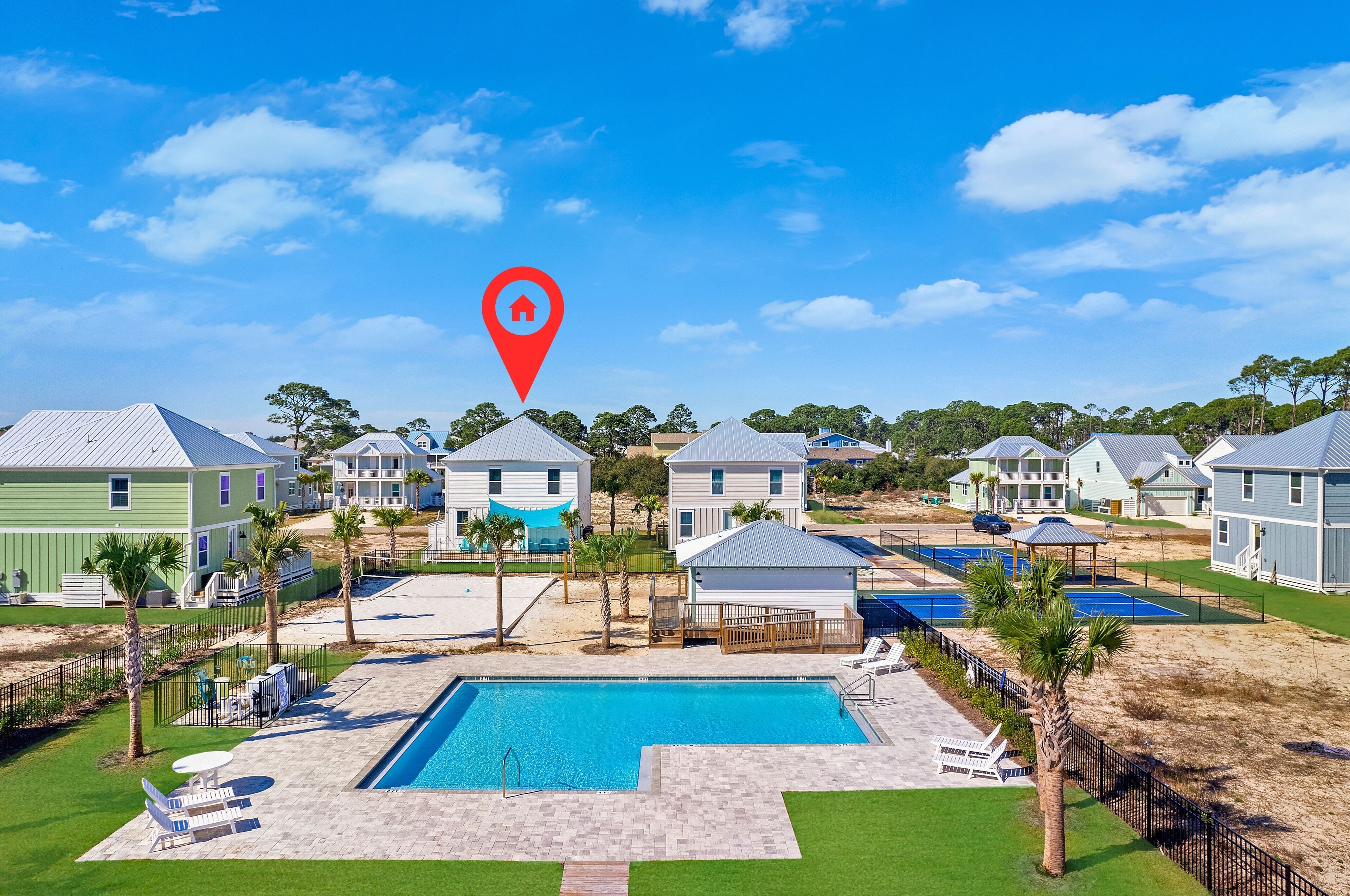 A residential area with a swimming pool, multiple houses, and a clear blue sky.