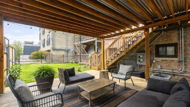An outdoor patio with wooden beams, a staircase, and a brick wall. - Charming & Comfy Gem ~ 10 Mins to Downtown ~Patio! (Chicago)