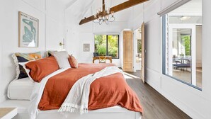 Een ruime slaapkamer met een groot bed, een kroonluchter en uitzicht op het omliggende landschap.