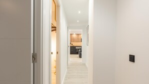Un couloir au plancher de bois menant à une cuisine.