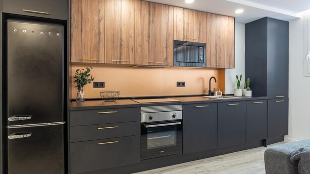 Une cuisine moderne avec des meubles de couleur sombre, un réfrigérateur en acier inoxydable, un four à micro-ondes encastré et un four traditionnel.
