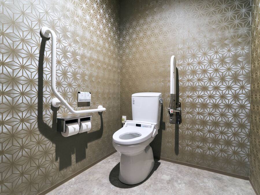A modern bathroom with a geometric patterned wall, a toilet, and a hand dryer.