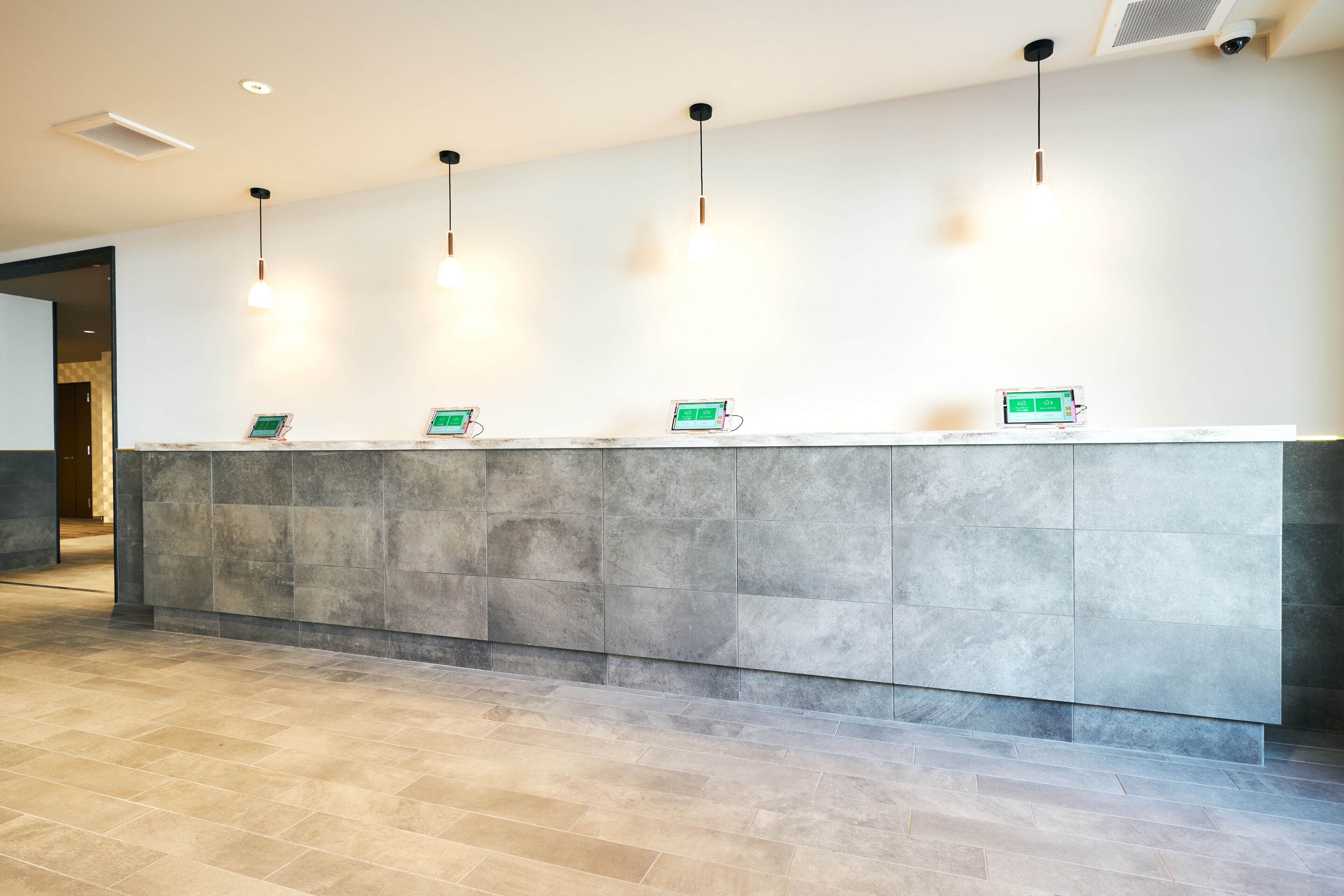 A reception desk with a marble counter and three digital displays.
