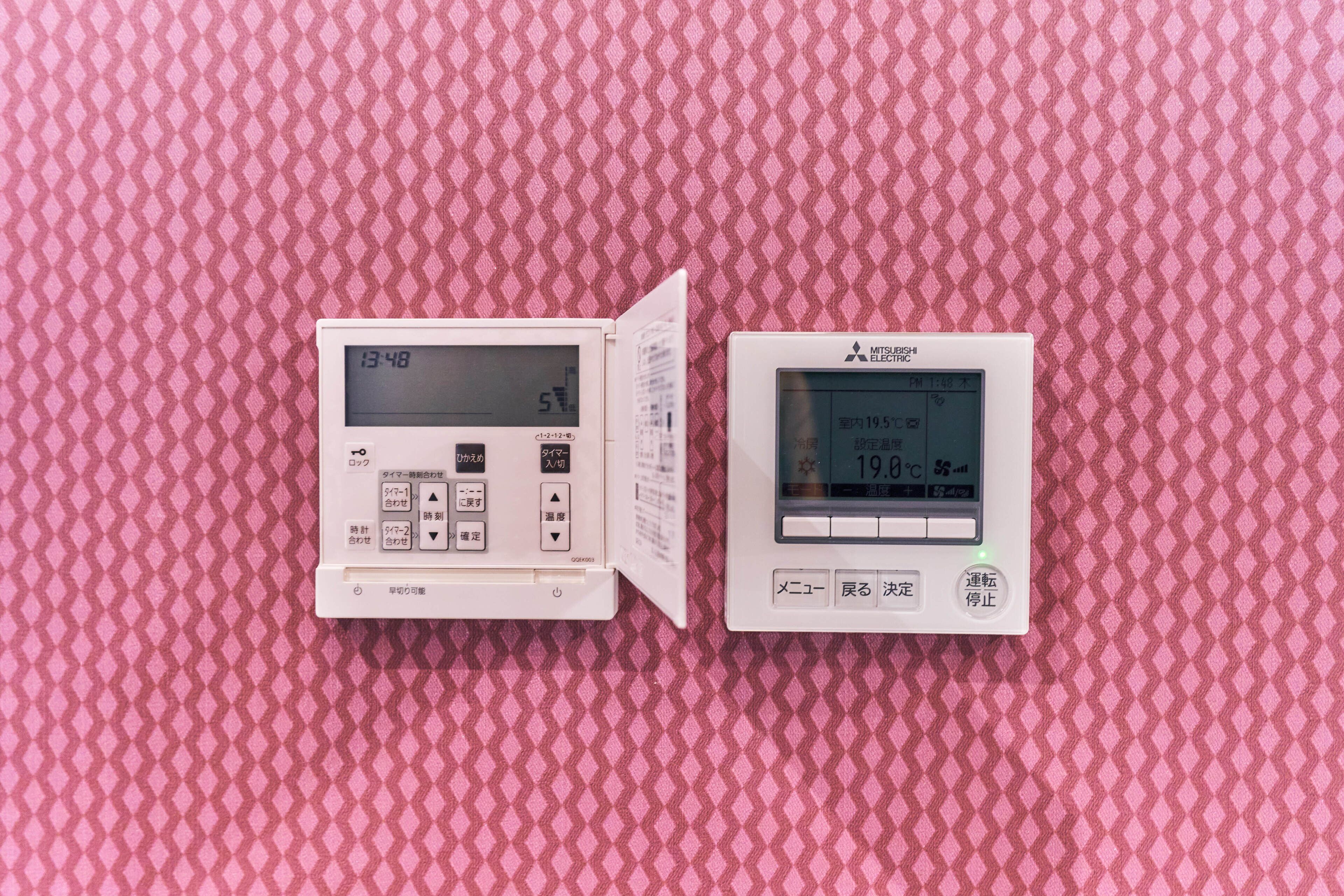 Two digital thermometers on a pink textured surface.