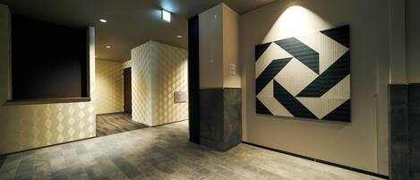A modern hallway with patterned walls, a geometric wall art piece, and a tiled floor.