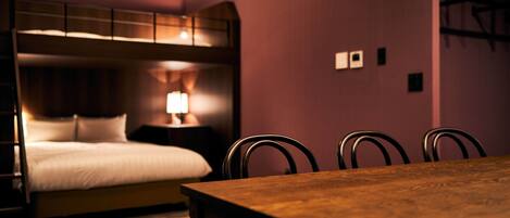 A hotel room with a bunk bed, a wooden dining table, and four chairs.