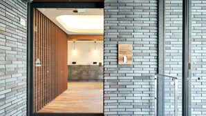 A modern reception area with a wooden slat partition, a reception desk, and a wall-mounted sign. - Rakuten STAY Kokura Station (Kitakyushu)