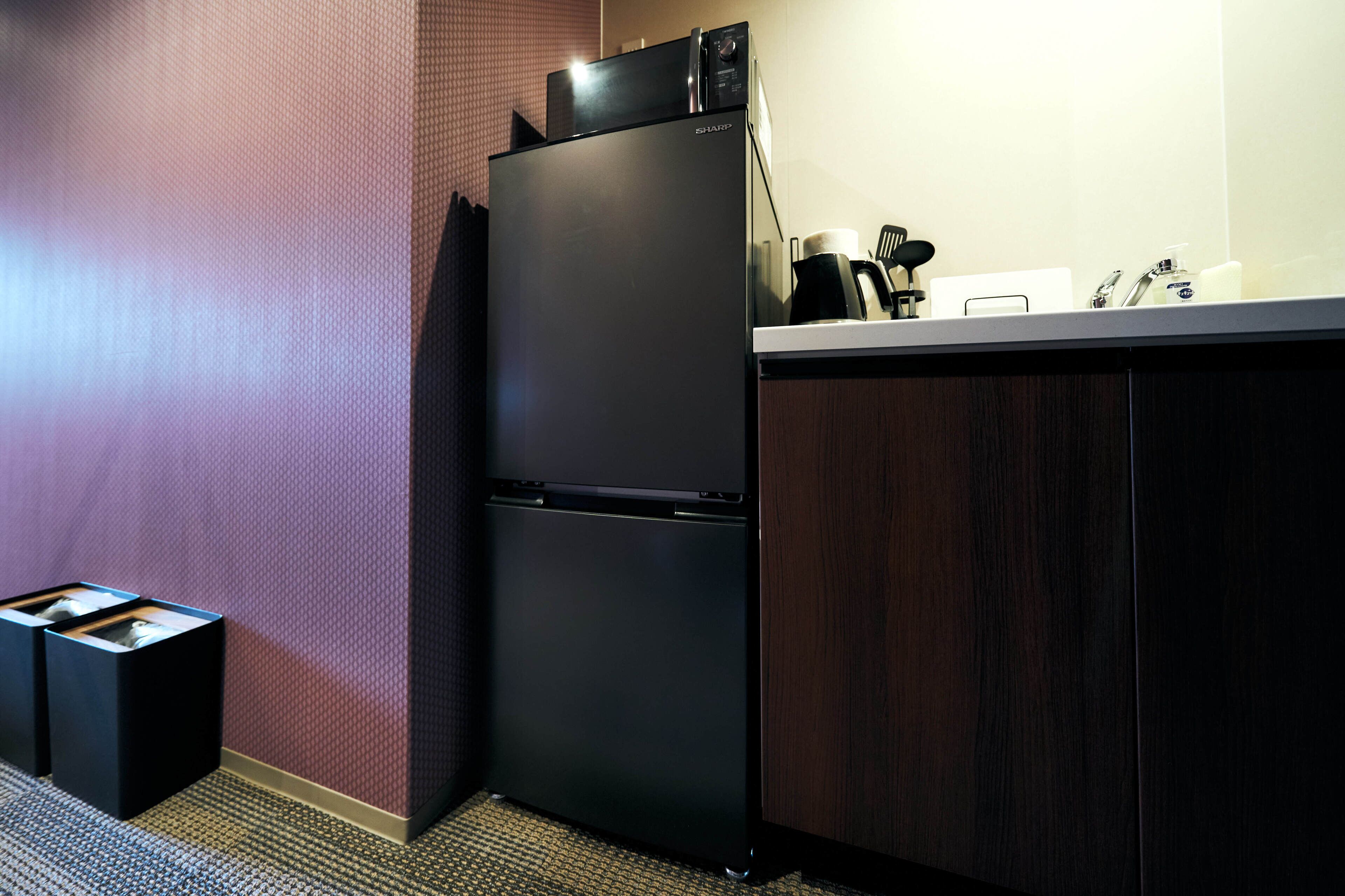 A kitchen with a black refrigerator, a coffee maker, and a sink.