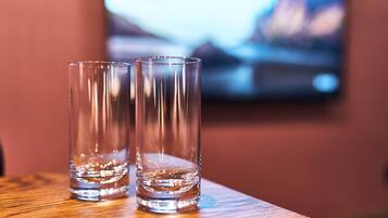 Two clear glasses on a wooden surface with a blurred background.