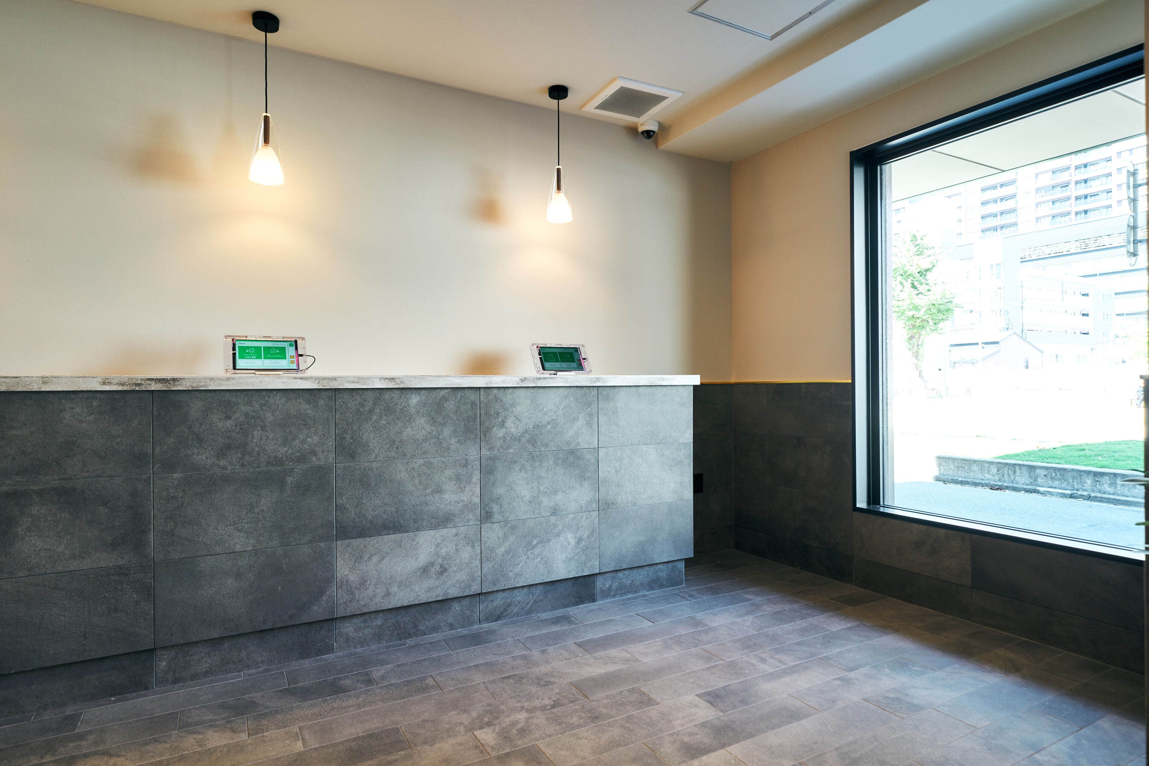 A reception area with a modern design, featuring a reception desk, two pendant lights, and a large window providing a view of the outside.