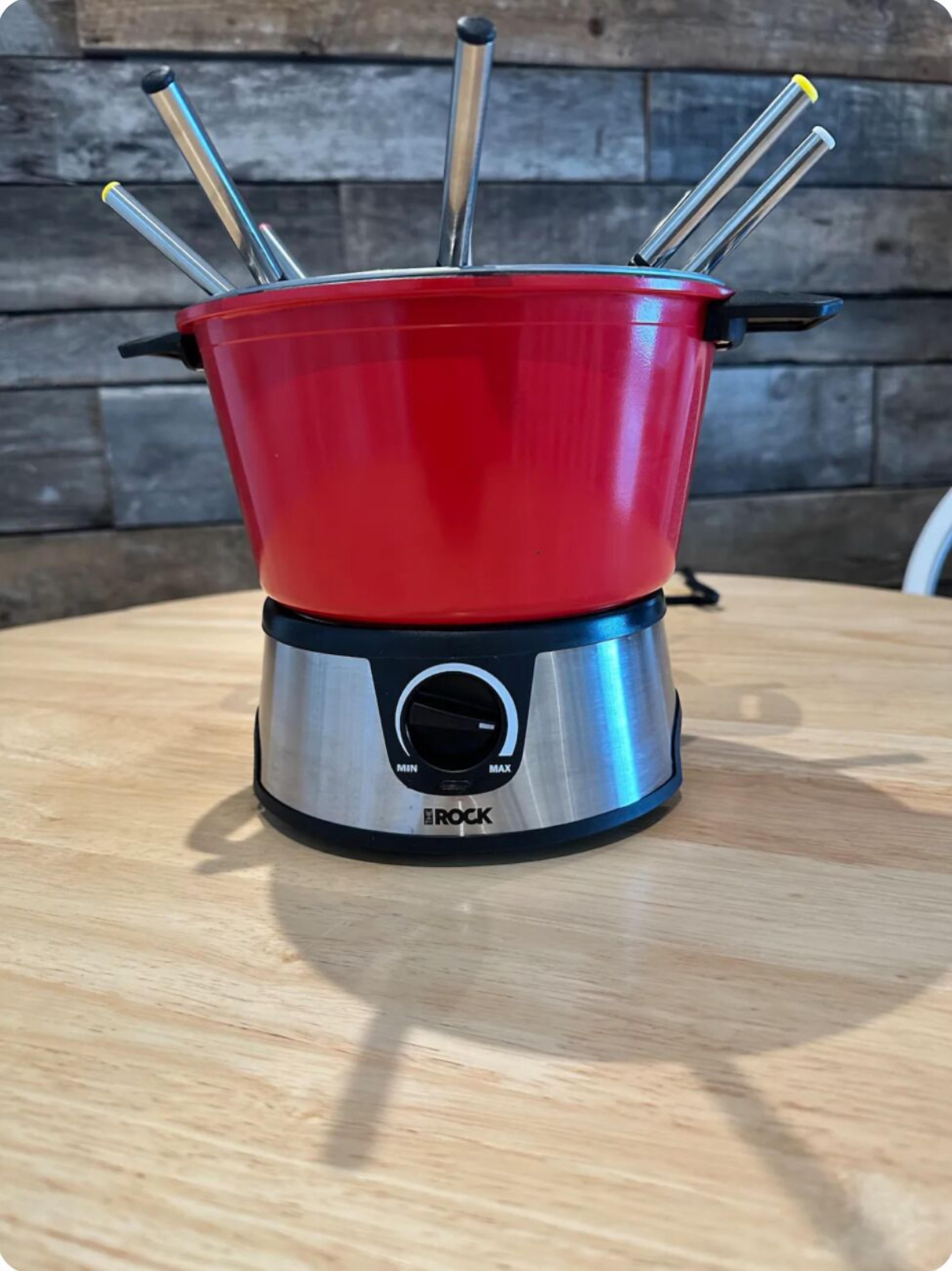 Une cuisinière électrique rouge, dotée d’une base métallique et d’un bouton de réglage.