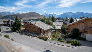 A mountain town with wooden buildings, a paved street, and a view of distant mountains. - Appartement du Poutat - Welkeys (Huez)