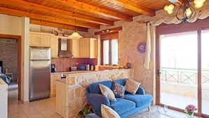Un salón acogedor con un sofá azul, una cocina con armarios de madera y una pared de piedra.