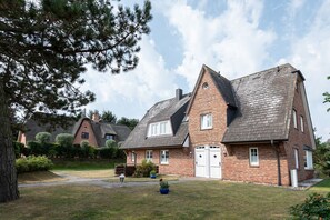 Ein traditionelles Backsteinhaus mit einem steilen Satteldach, einer angebauten Garage und einem gepflegten Rasen.