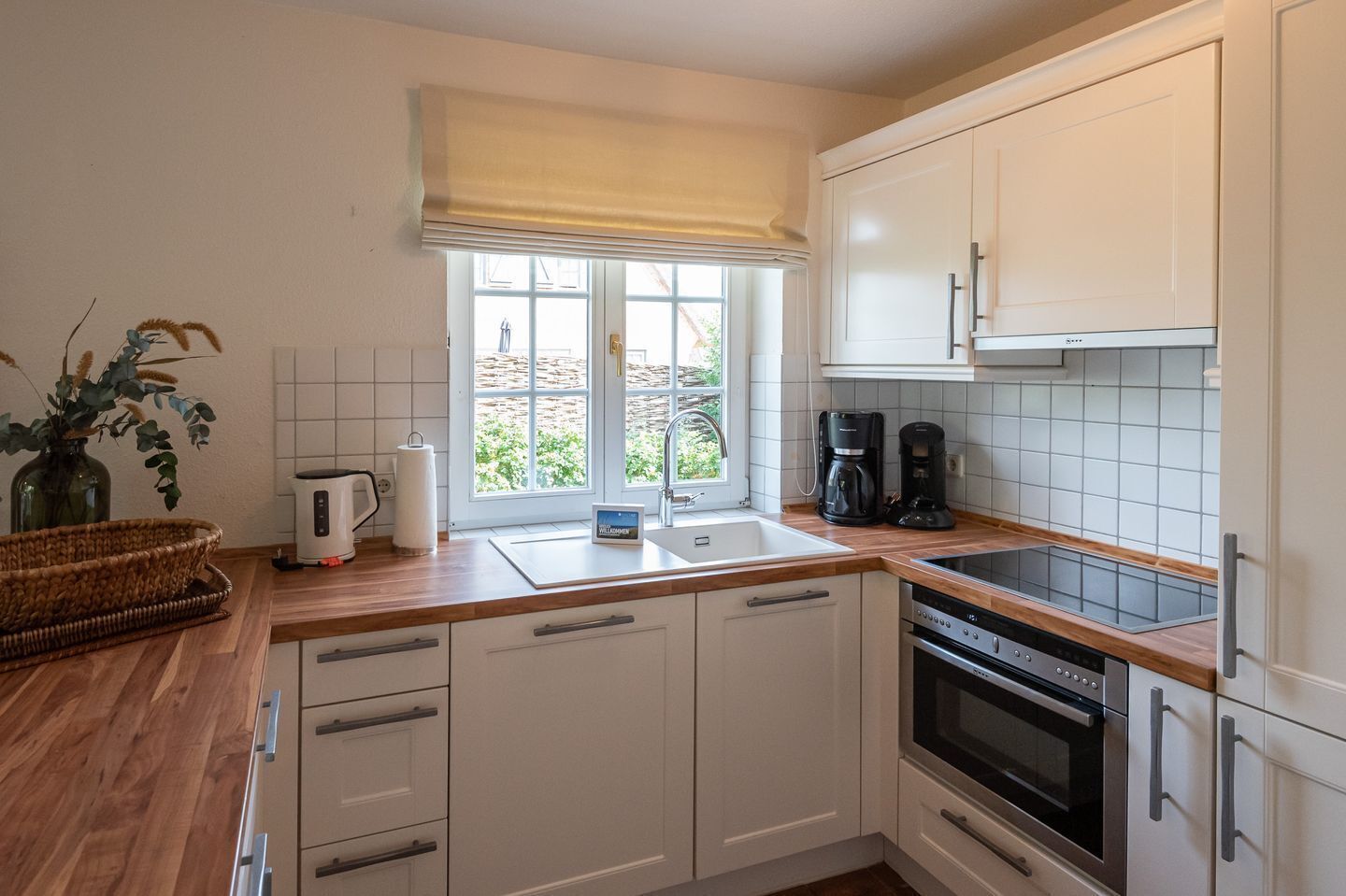 A kitchen with white cabinets, a window with a view, a coffee maker, and a toaster.