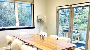 Un comedor amplio con una mesa y sillas de madera, ventanas grandes y vistas al exterior.